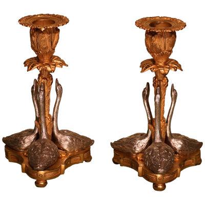 A pair of 19th century ormolu and silver candlesticks with swans